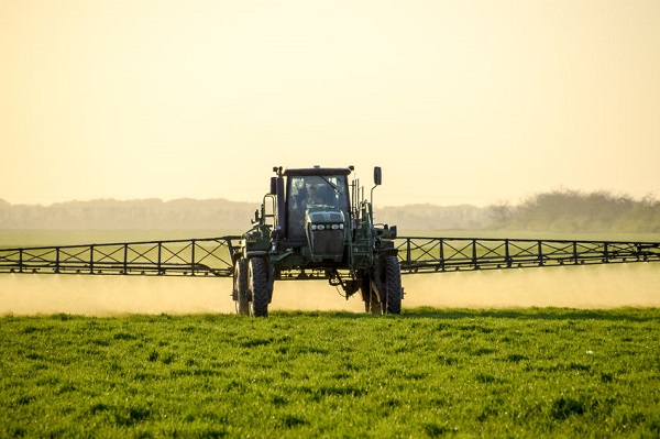 Traktor sprüht Gift auf Pflanzen