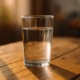 Ein Glas Wasser auf einem Holztisch im warmen Morgenlicht – Symbol für Klarheit, Einfachheit und innere Ordnung beim Fasten.